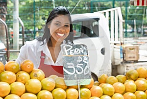 Happy mexican saleswoman with oranges on a farmers market