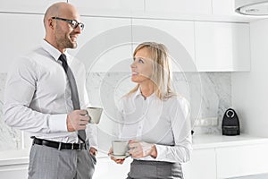 Happy mid adult business couple having coffee in kitchen