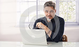 Happy mid adult man working with laptop at home