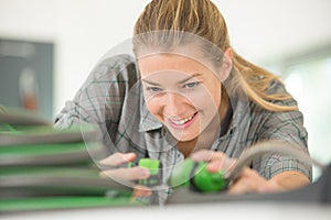 happy mid adult saleswoman holding air compressor hose in hardware-store