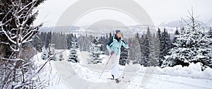 Happy mid adult woman cross country skiing outdoors in winter nature, Tatra mountains Slovakia.