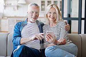 Happy mid age couple using cellphone, download new mobile application