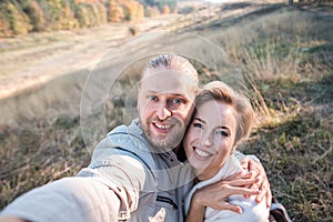 Happy middle age couple make selfie outdoors.