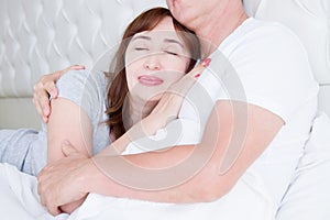 Happy middle age family couple in bed. White interior. Love and healthy relationships. Husband and wife portrait. Cropped image