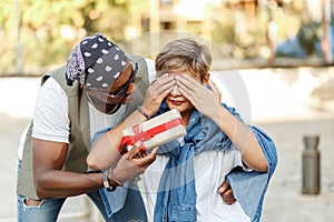 Happy middle age interracial couple sitting . Man giving Valentine's day gift to his woman,girlfriend or wife