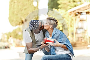 Happy middle age interracial couple sitting . Man giving Valentine's day gift to his woman,girlfriend or wife