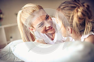 Happy middle age mother with her daughter lying on a bed.