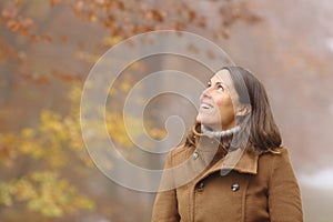 Happy middle age woman contemplating in a forest in fall