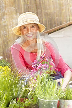 Happy middle age woman with flowers in her garden