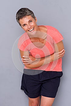 Happy middle age woman laughing by gray background