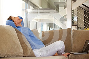 Happy middle age woman sitting on sofa with laptop