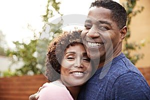 Happy middle aged African American  couple embracing smile to camera, close up