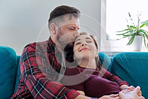 Happy middle-aged couple embracing at home on the couch