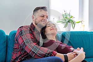 Happy middle-aged couple embracing at home on the couch