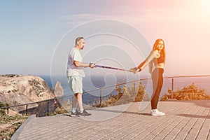 Happy Middle aged couple or friends practicing nordic walking in park near sea. Mature couple with trekking poles