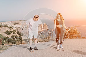 Happy Middle aged couple or friends practicing nordic walking in park near sea. Mature couple with trekking poles