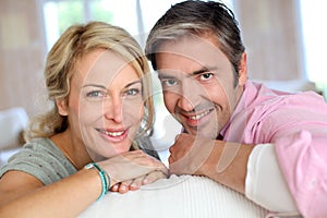 Happy middle-aged couple leaning on sofa