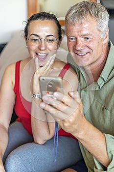 Happy middle-aged couple looking a mobile phone