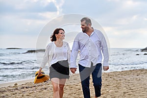 Happy middle-aged couple walking together on the beach.