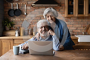 Happy middle aged family couple enjoying using computer applications.