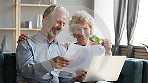 Happy middle aged family couple looking through paper documents.