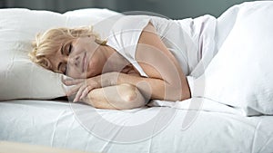 Happy middle-aged female sleeping in bed on orthopedic mattress, healthy rest photo