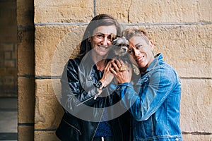 Happy middle aged lesbian couple hugging their yorkshire terrier