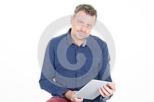 Happy middle aged man in casual blue shirt standing using tablet computer isolated over white background