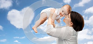 Happy middle-aged mother with baby over sky