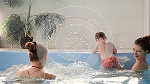 Happy middle-aged mother swimming with cute adorable baby in swimming pool. Smiling mom and little child, newborn girl