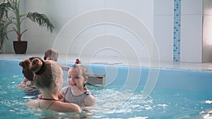 Happy middle-aged mother swimming with cute adorable baby in swimming pool. Smiling mom and little child, newborn girl