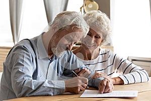 Happy middle aged retired couple signing marriage contract.