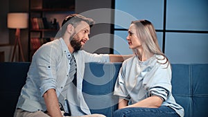 Happy middle-aged spouses talking about relationships, sitting on soft sofa in living room at home