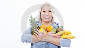 Happy middle aged woman with blond hair and beautiful smile holds products from the store in paper bag of vegetables in her hands