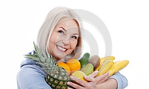 Happy middle aged woman with blond hair and beautiful smile holds products from the store in paper bag of vegetables in her hands