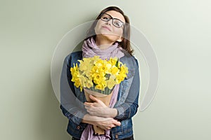 Happy middle aged woman with bouquet of yellow flowers, green wall background