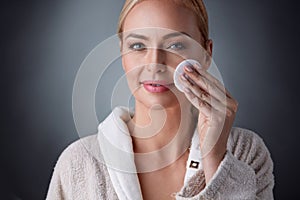 Happy middle aged woman cleaning face and removing make up with