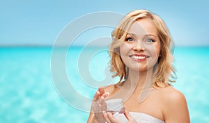 Happy middle aged woman with cream jar over sea