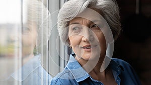 Happy middle aged woman dreaming near window.