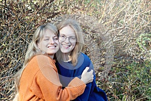 Happy middle aged woman enjoying love of her teenage daughter on Mother`s Day. Portrait of hugging mother and daughter, outdoors