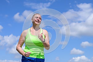 Happy middle-aged woman grinning as she jogs outdoors in summer