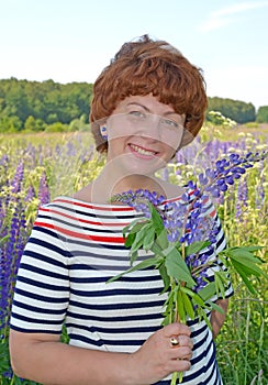 Happy middle-aged woman holding a bouquet of blooming lupins in her hand