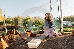 Happy middle aged woman on a private farm feeding chickens