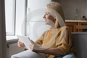 Happy middle aged woman relaxing on couch in good thoughts