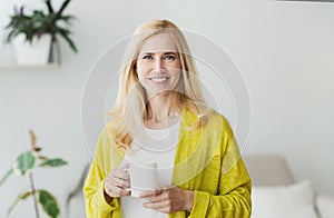 Happy middle-aged woman resting with cup of tea