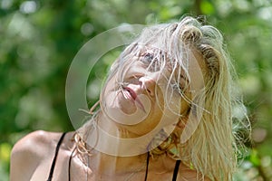 Happy middle aged woman with wet hair smiling in the forest