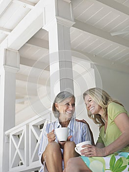 Happy Middle Aged Women On Verandah With Cups