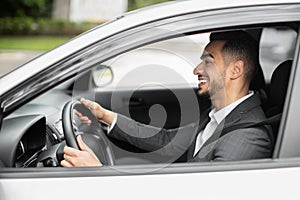 Happy middle eastern businessman driving his new auto, panorama