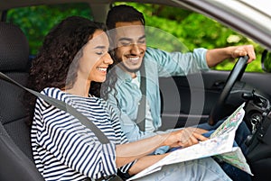 Happy middle-eastern couple sitting in car, planning journey