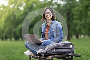 Happy Middle Eastern Female Student Sitting On Bench Outdoors With Laptop